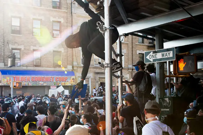 A photo of a man climbing a pole during a protest in Flatbush this weekend